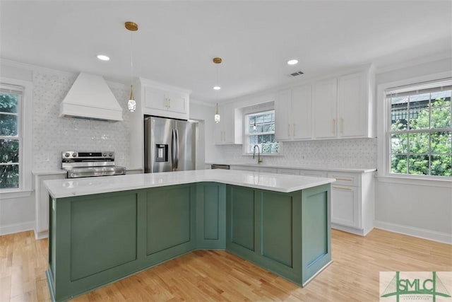 kitchen with stainless steel appliances, premium range hood, a sink, white cabinetry, and green cabinetry