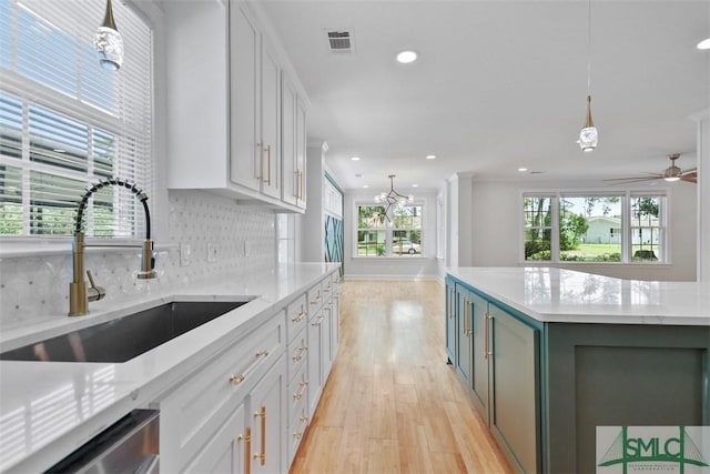 kitchen featuring visible vents, light wood-style flooring, backsplash, stainless steel dishwasher, and a sink