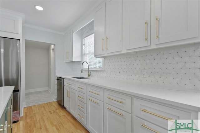 kitchen with stainless steel appliances, a sink, white cabinets, decorative backsplash, and crown molding