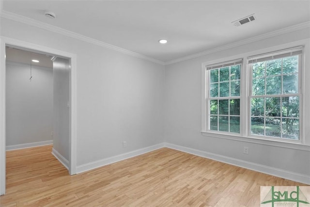 spare room with light wood finished floors, ornamental molding, and visible vents