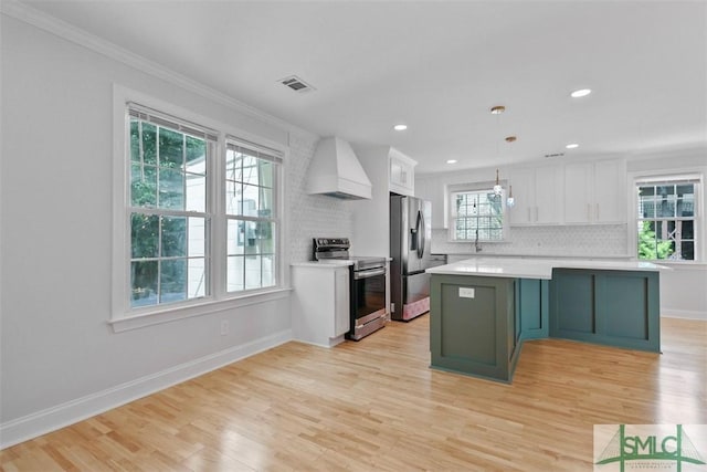 kitchen with custom exhaust hood, white cabinetry, appliances with stainless steel finishes, and light countertops