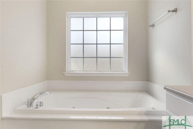 bathroom with a whirlpool tub, vanity, and a healthy amount of sunlight