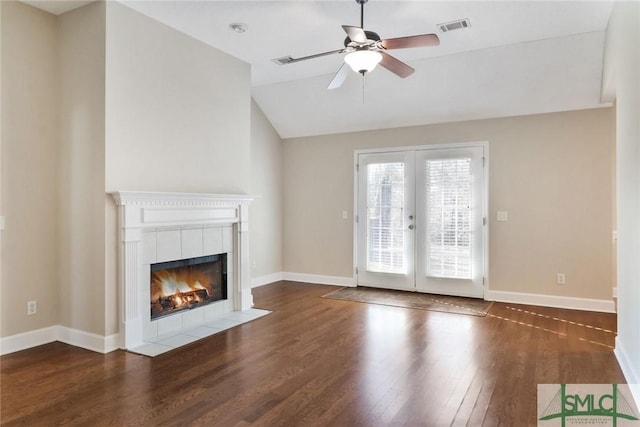 unfurnished living room with french doors, visible vents, a tiled fireplace, vaulted ceiling, and wood finished floors