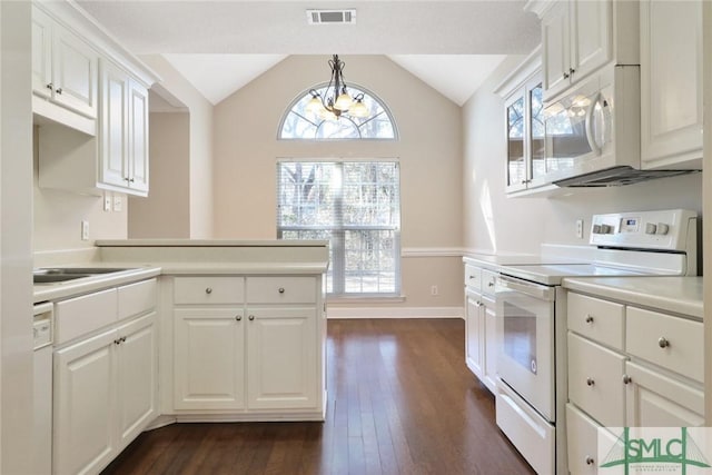 kitchen featuring lofted ceiling, white appliances, dark wood-style flooring, visible vents, and a wealth of natural light