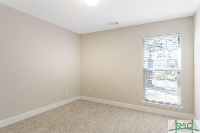 empty room featuring light colored carpet, a healthy amount of sunlight, and baseboards