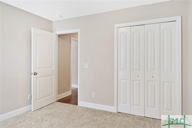 unfurnished bedroom with carpet floors, a closet, and baseboards