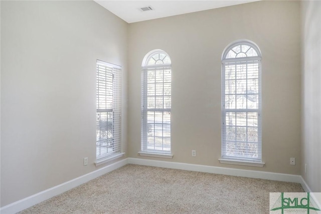 spare room featuring carpet floors, a healthy amount of sunlight, visible vents, and baseboards