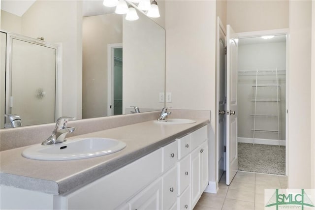 bathroom with tile patterned flooring, a sink, a walk in closet, and a shower stall