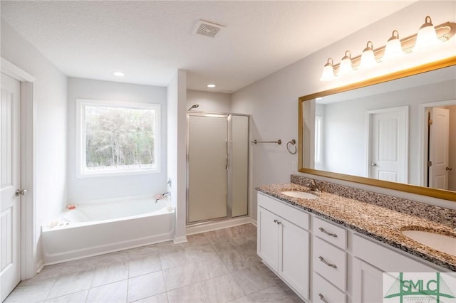 bathroom featuring a stall shower, visible vents, a garden tub, and a sink