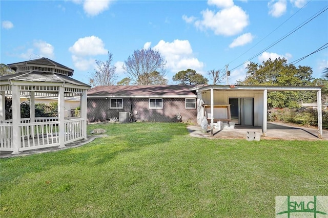 back of house featuring a patio area, a gazebo, brick siding, and a yard