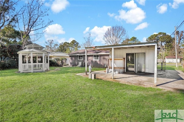 rear view of house featuring a patio area, a yard, brick siding, and a gazebo