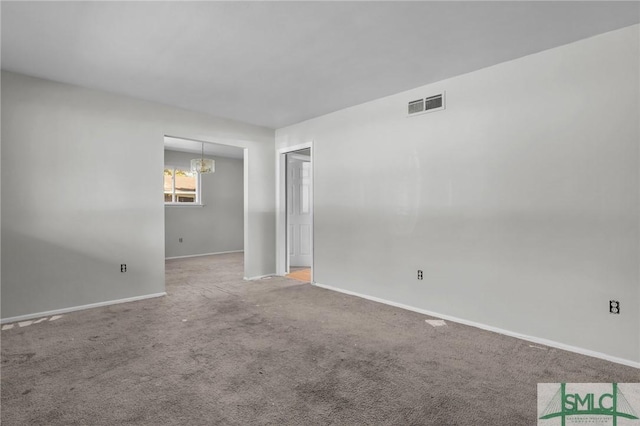 carpeted spare room featuring a chandelier, visible vents, and baseboards