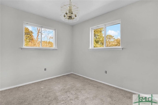 carpeted spare room featuring baseboards and a chandelier