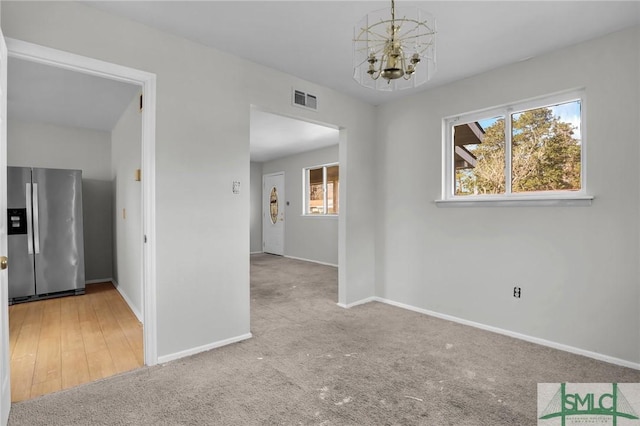 interior space with baseboards, carpet flooring, visible vents, and an inviting chandelier