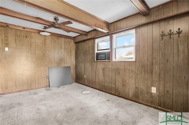 carpeted empty room with beam ceiling, wood walls, and baseboards