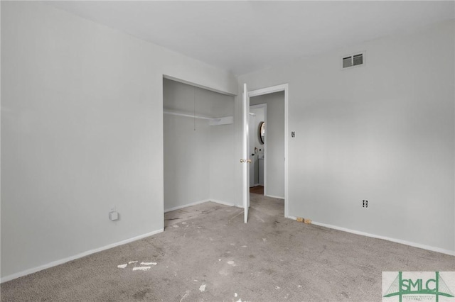 unfurnished bedroom featuring carpet, a closet, visible vents, attic access, and baseboards