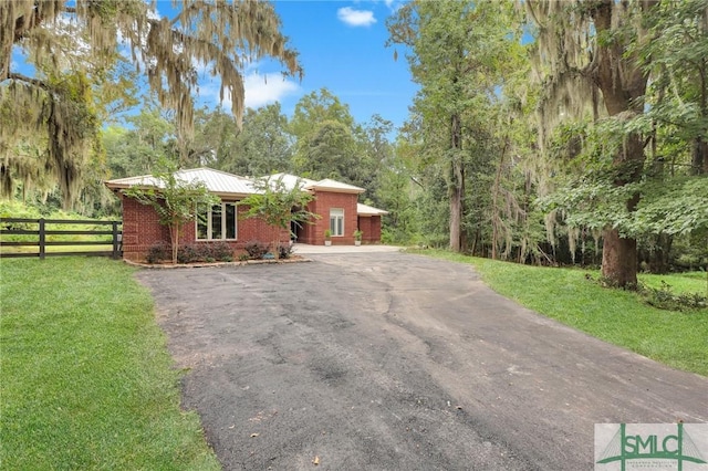 view of front of property with driveway, fence, a front lawn, and brick siding