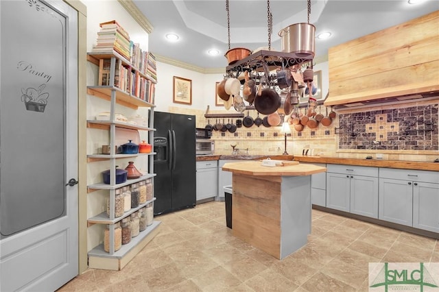 kitchen featuring recessed lighting, a kitchen island, wooden counters, decorative backsplash, and black refrigerator with ice dispenser