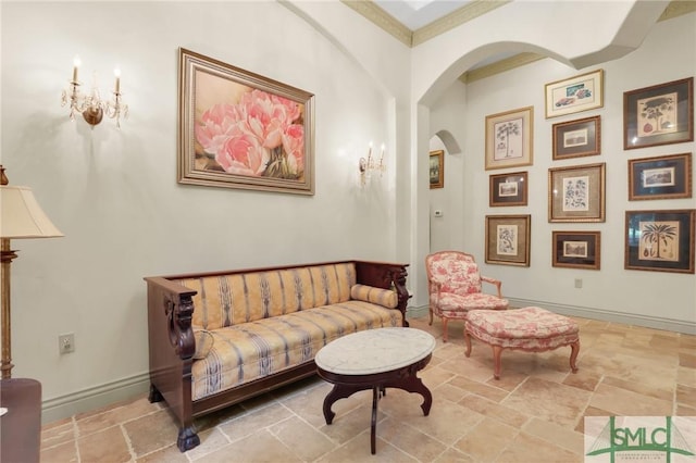 living area featuring arched walkways, stone tile flooring, and baseboards