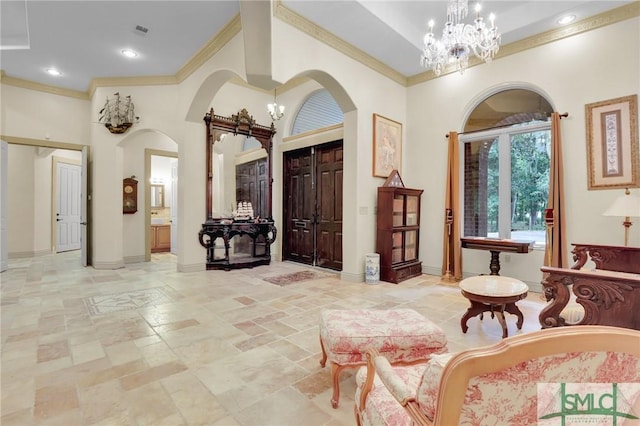 entryway featuring ornamental molding, visible vents, a towering ceiling, and an inviting chandelier