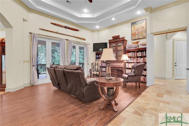 living area with arched walkways, french doors, a raised ceiling, a towering ceiling, and baseboards