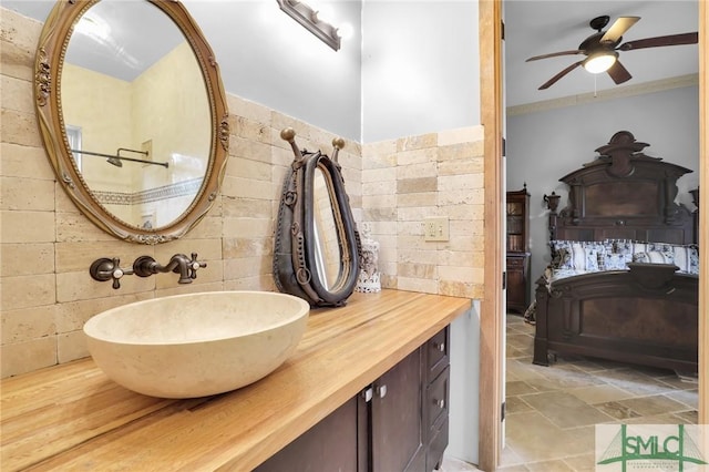 bathroom featuring a ceiling fan, tile walls, vanity, and crown molding