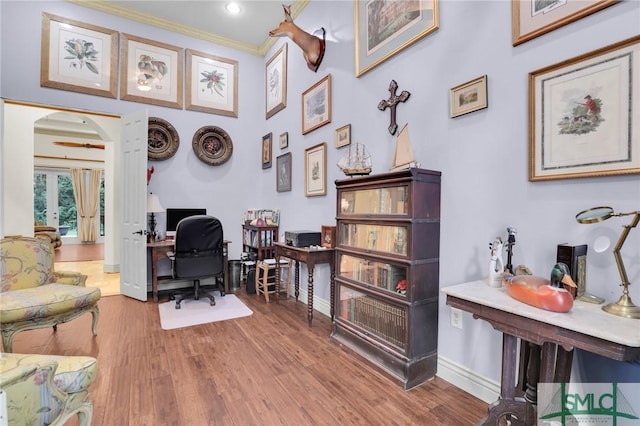 office area with arched walkways, ornamental molding, wood finished floors, and baseboards