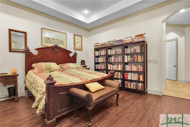 bedroom with baseboards, arched walkways, wood finished floors, and ornamental molding