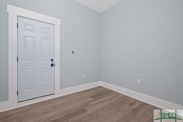 spare room with baseboards and wood finished floors