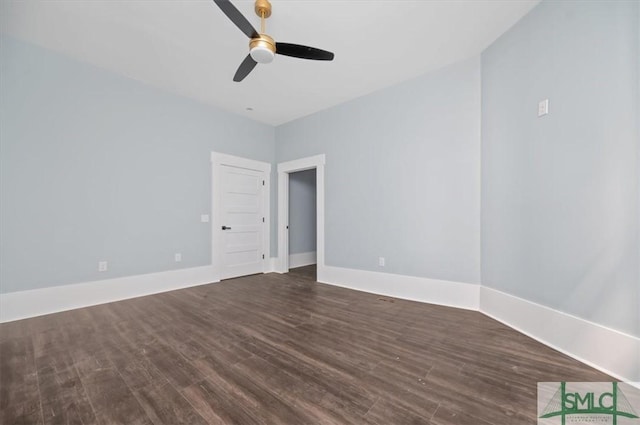 spare room featuring ceiling fan, dark wood-type flooring, and baseboards