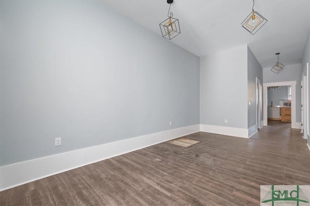 unfurnished room featuring dark wood-type flooring and baseboards