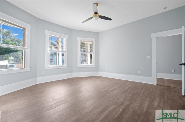 empty room with dark wood-style floors, ceiling fan, and baseboards