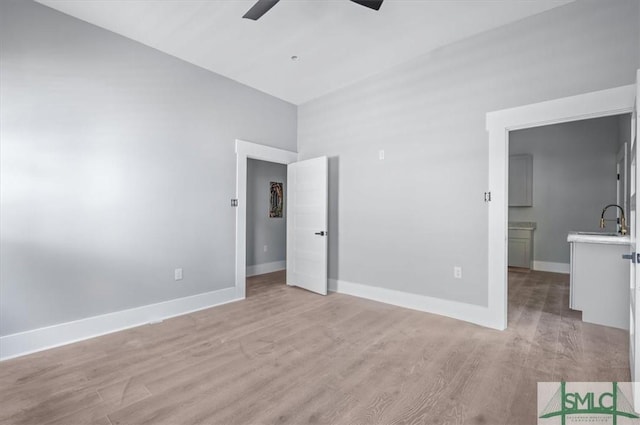 unfurnished bedroom with light wood finished floors, a sink, a ceiling fan, and baseboards