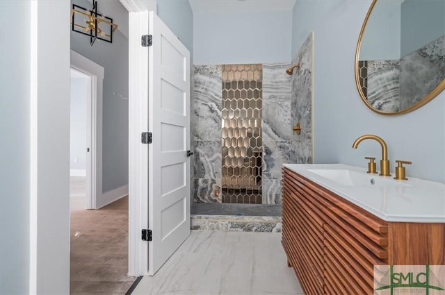 full bath with marble finish floor, tiled shower, and vanity