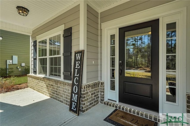 entrance to property featuring brick siding and a porch