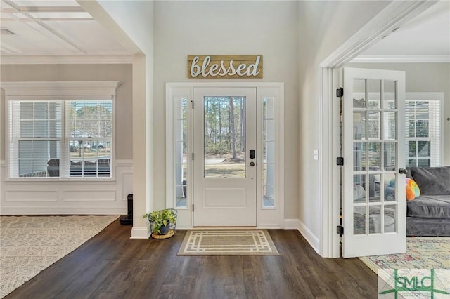 entryway with a wainscoted wall, ornamental molding, wood finished floors, and baseboards