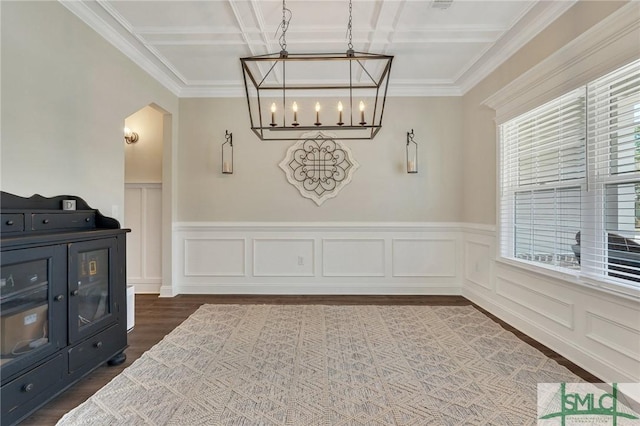 dining room featuring arched walkways, dark wood-style flooring, a wainscoted wall, a notable chandelier, and ornamental molding