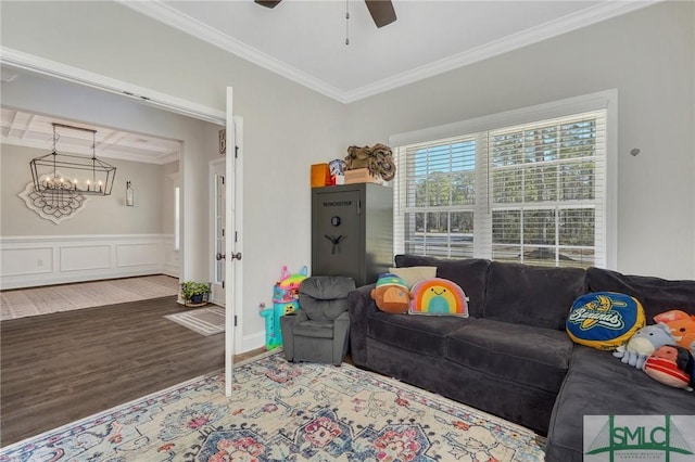 living area featuring a wainscoted wall, ceiling fan, ornamental molding, and wood finished floors