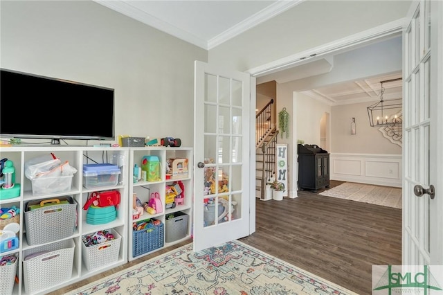 rec room featuring a wainscoted wall, wood finished floors, crown molding, french doors, and a notable chandelier