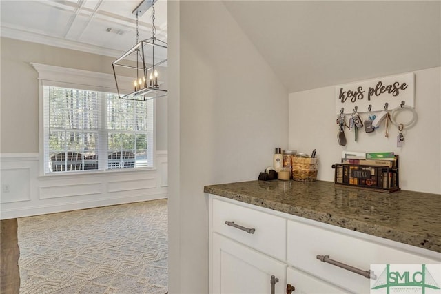 bar featuring lofted ceiling, an inviting chandelier, a decorative wall, and wainscoting