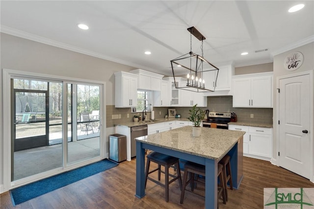 kitchen with a breakfast bar area, stainless steel appliances, white cabinets, a center island, and crown molding