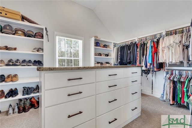 spacious closet with vaulted ceiling and light colored carpet