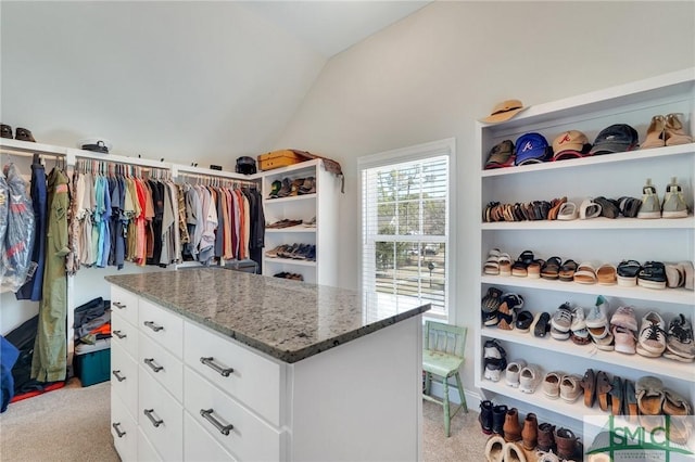 walk in closet with light carpet and vaulted ceiling