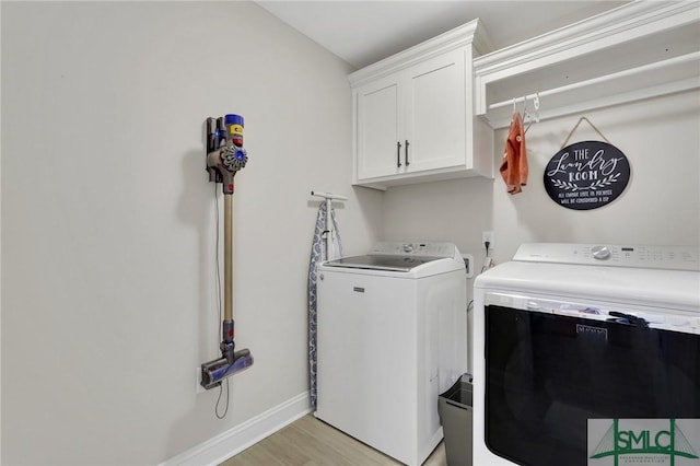 washroom with baseboards, cabinet space, washer and clothes dryer, and light wood finished floors