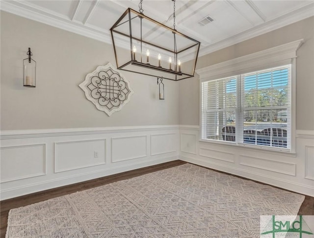 unfurnished dining area featuring a wainscoted wall, visible vents, a notable chandelier, and wood finished floors