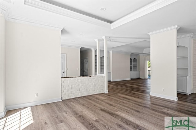 unfurnished living room featuring decorative columns, crown molding, a raised ceiling, and wood finished floors