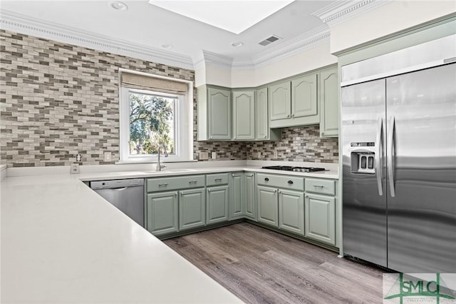 kitchen with tasteful backsplash, dark wood finished floors, ornamental molding, stainless steel appliances, and light countertops