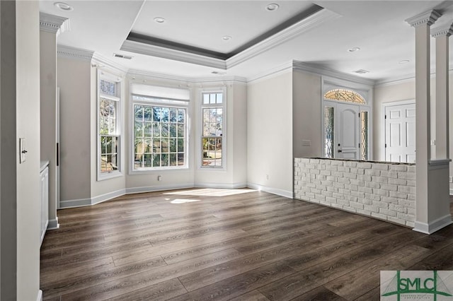 empty room with wood finished floors, visible vents, baseboards, ornamental molding, and a raised ceiling