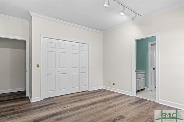 unfurnished bedroom featuring a closet, crown molding, baseboards, and wood finished floors