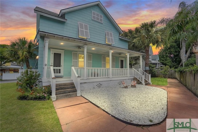 view of front of home with a porch, a front yard, and fence